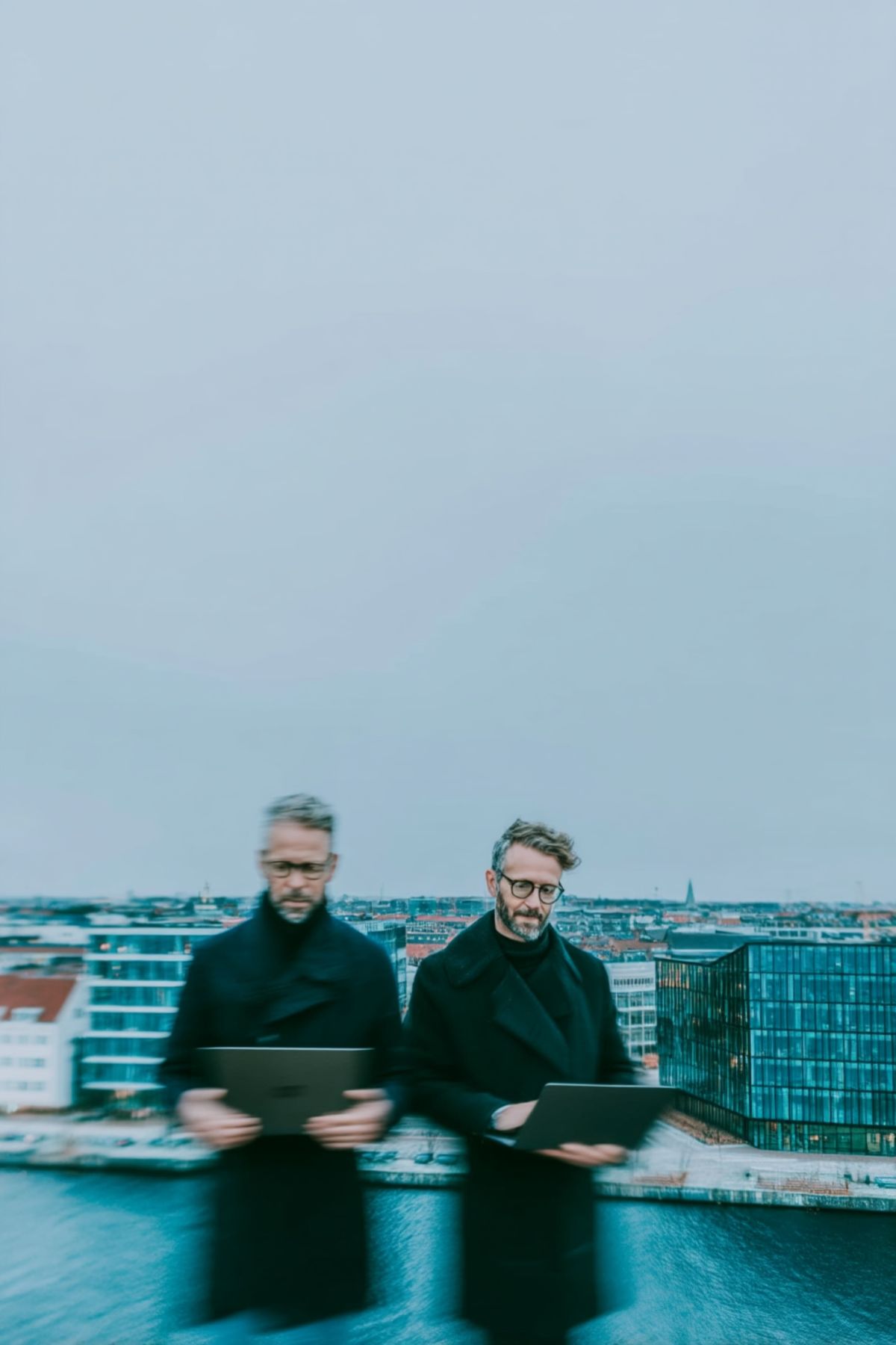 To rådgivere i mørke frakker på en tagterrasse over byen